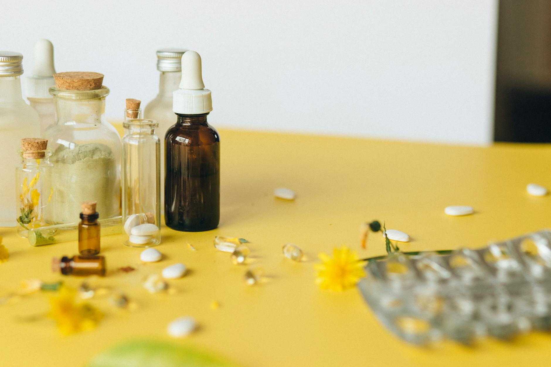 Main tenant un flacon de granules homéopathiques sur fond clair