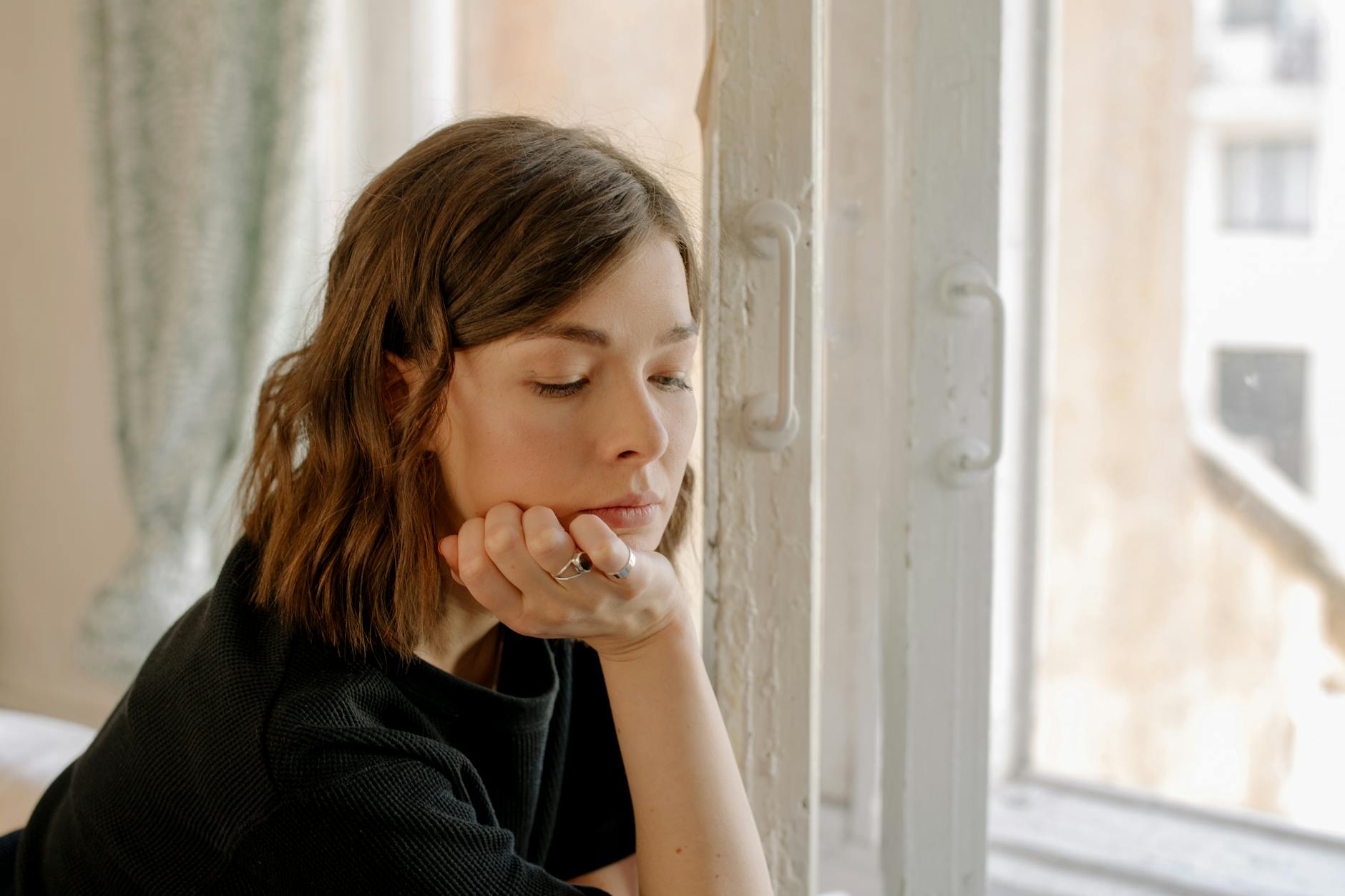 Femme pensive près d'une fenêtre dans une lumière douce